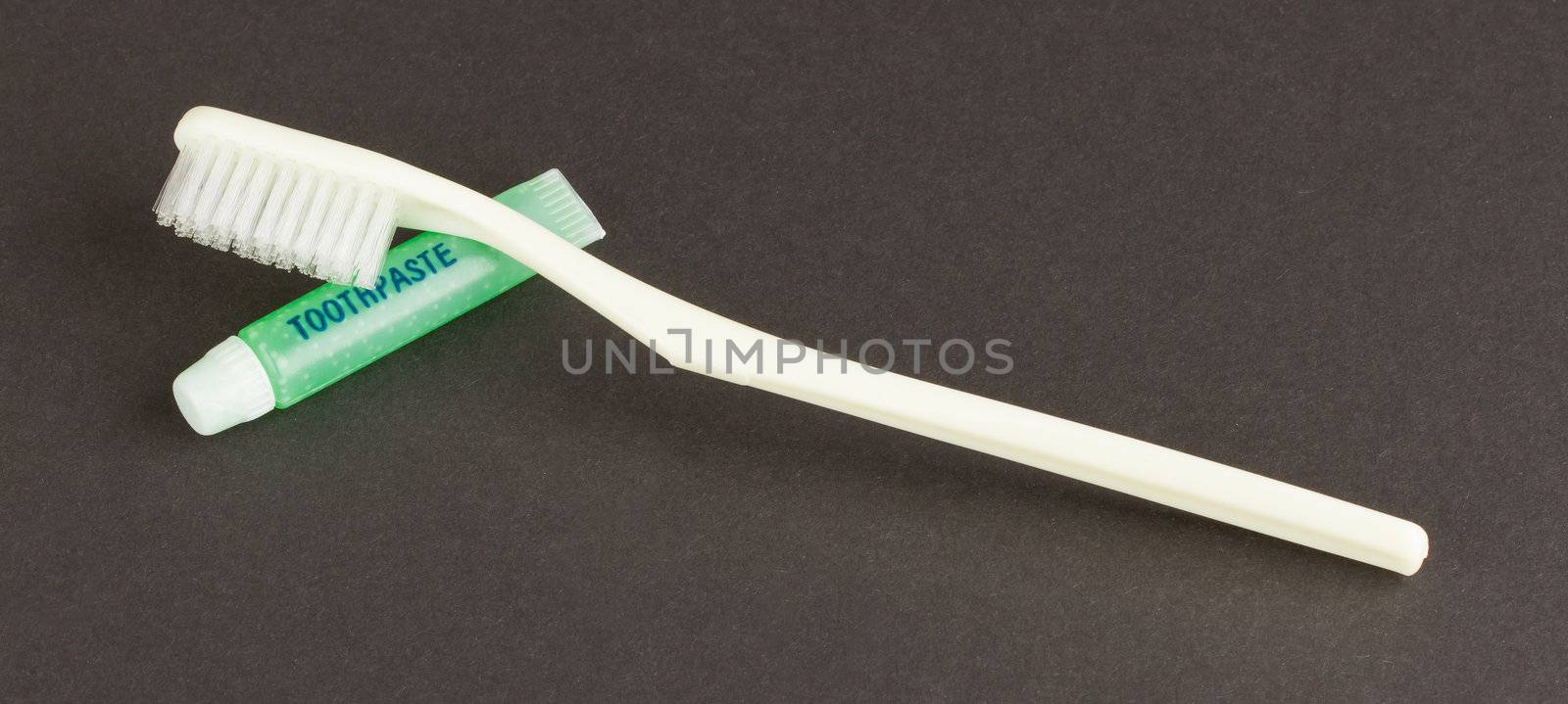 Toothbrush and green toothpaste isolated on a grey background