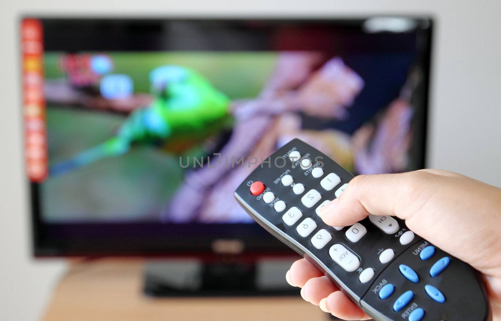 Hand pointing a tv remote control towards the television