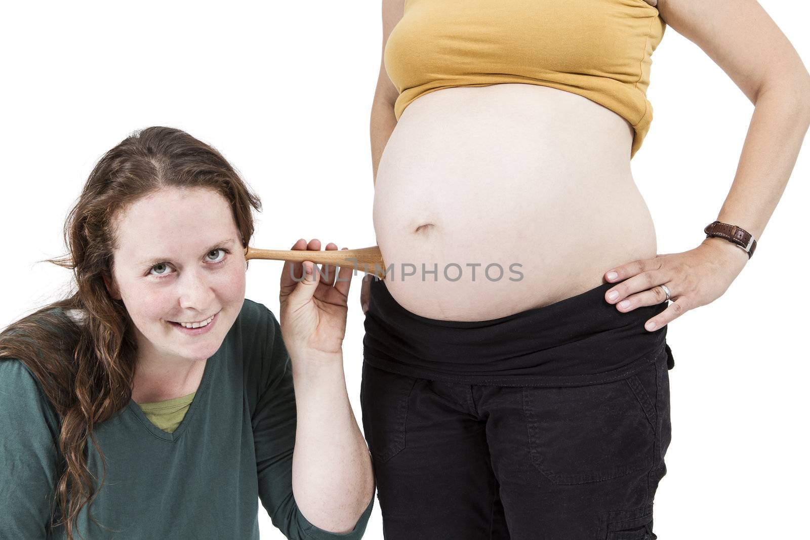 young midwife listening at human belly. pregnant woman standing while midwife is sitting in front. horizontal picture isolated on white