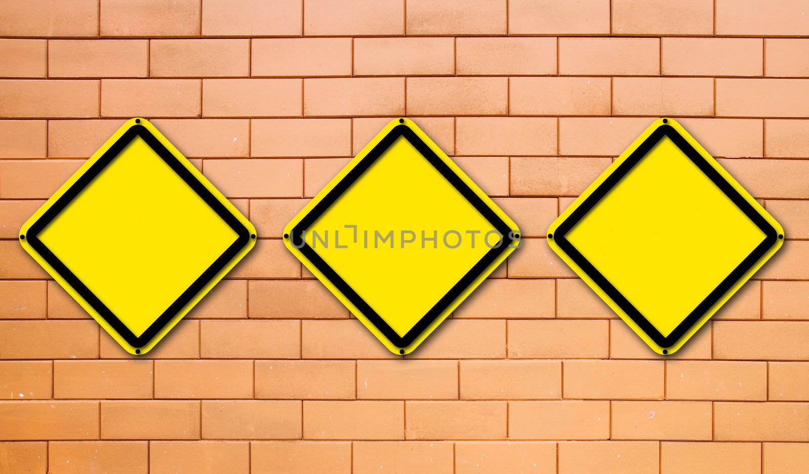 Three blank yellow traffic sign on brick wall background