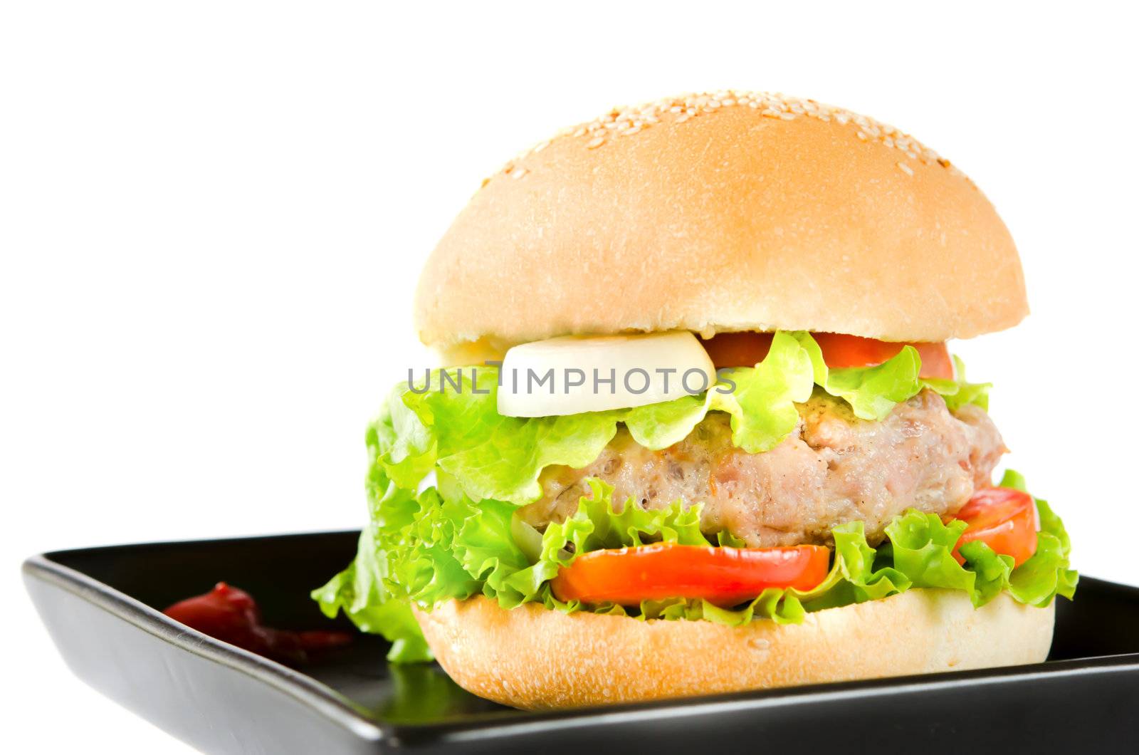big hamburger with tomato sauce on black dish 