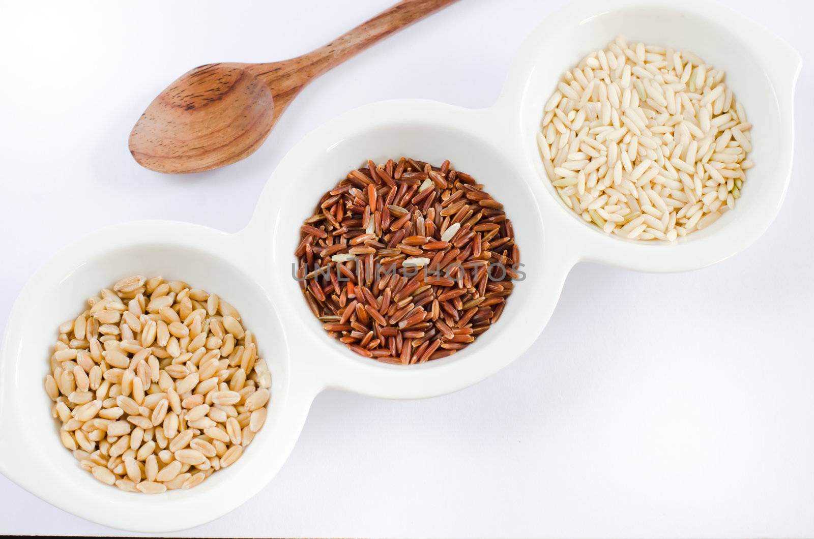  rice , red rice , wheat  grains on white bowl and wooden spoon
