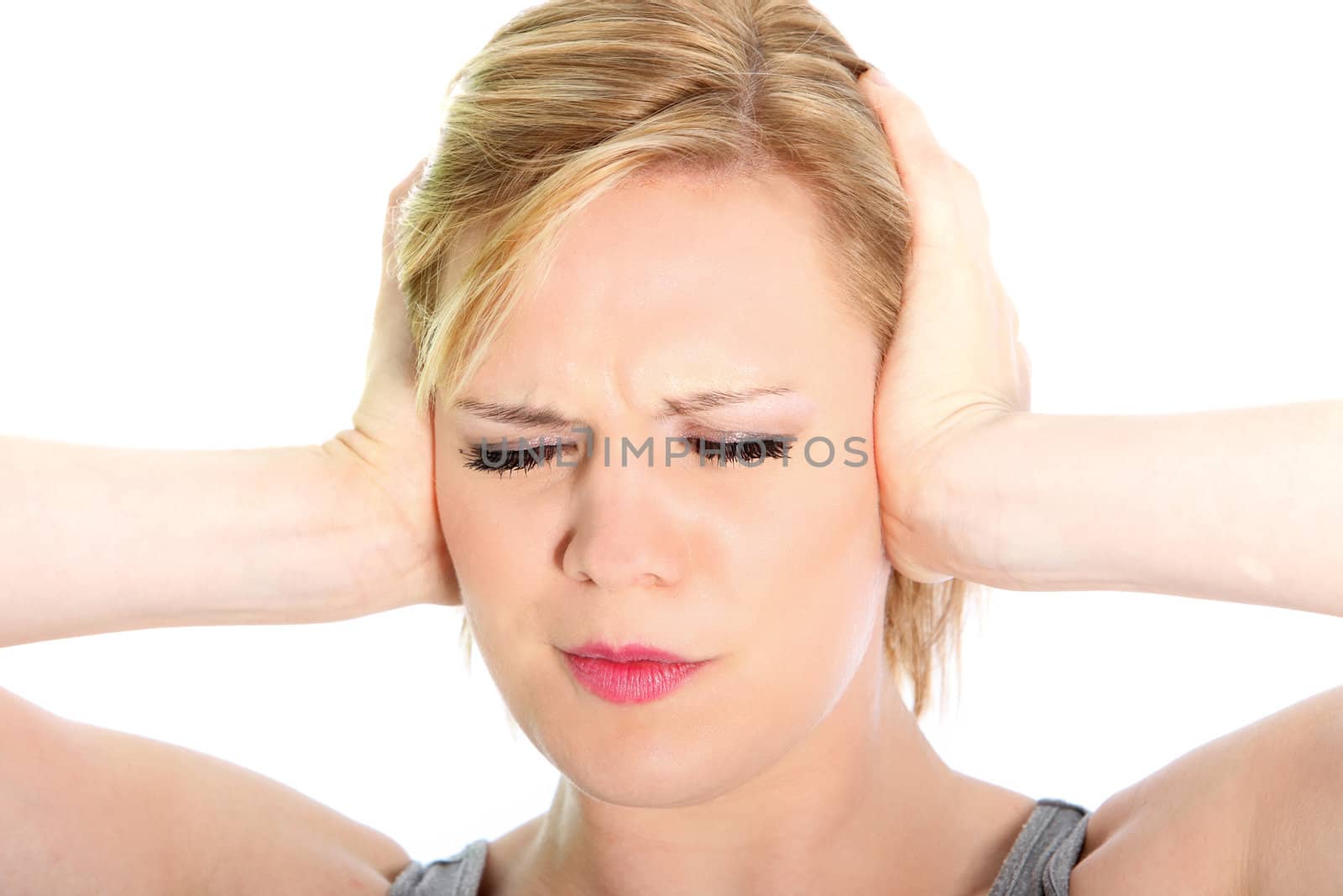 Woman suffering from a headache grimacing and holding her hands to her ears to relieve the throbbing, closeup studio head portrait on white