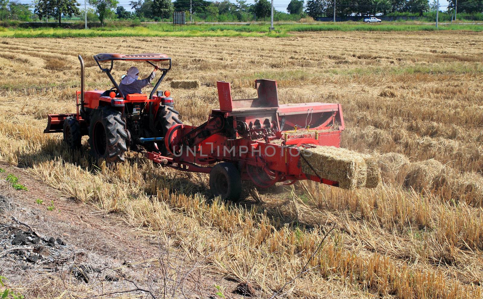 farmer and tractor packing straw in the field at Thailand by geargodz