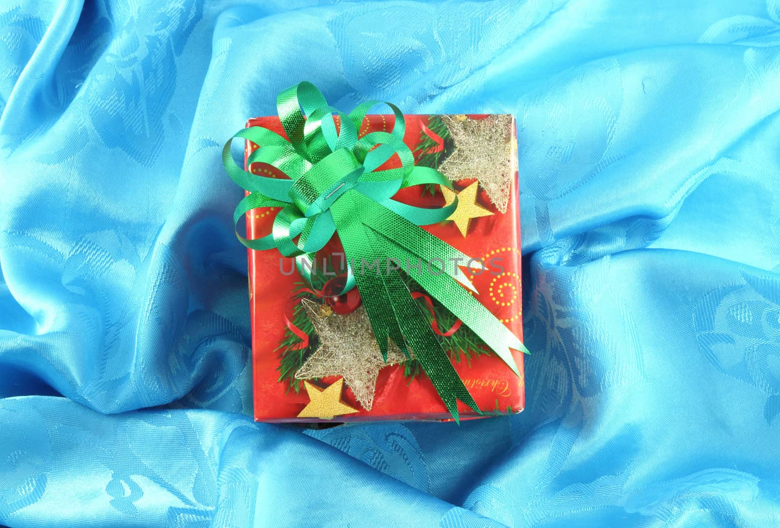 red gift box with green ribbon on blue satin by geargodz