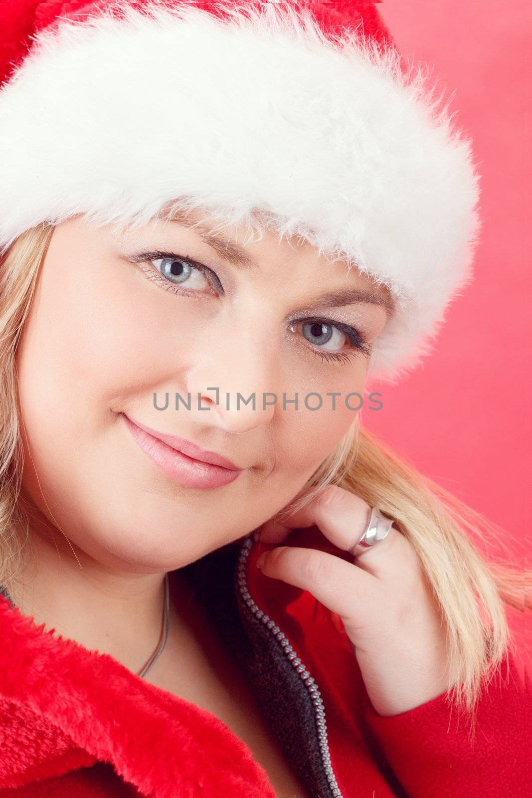 Portrait of joyful pretty woman in red santa claus hat smiling on red background