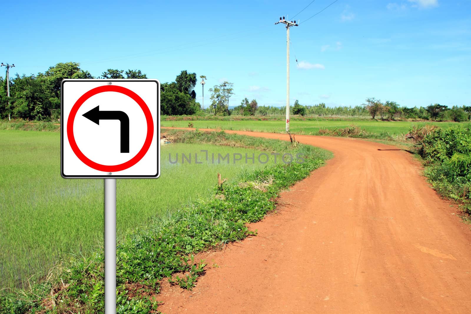 Turn left sign with soil road in countryside