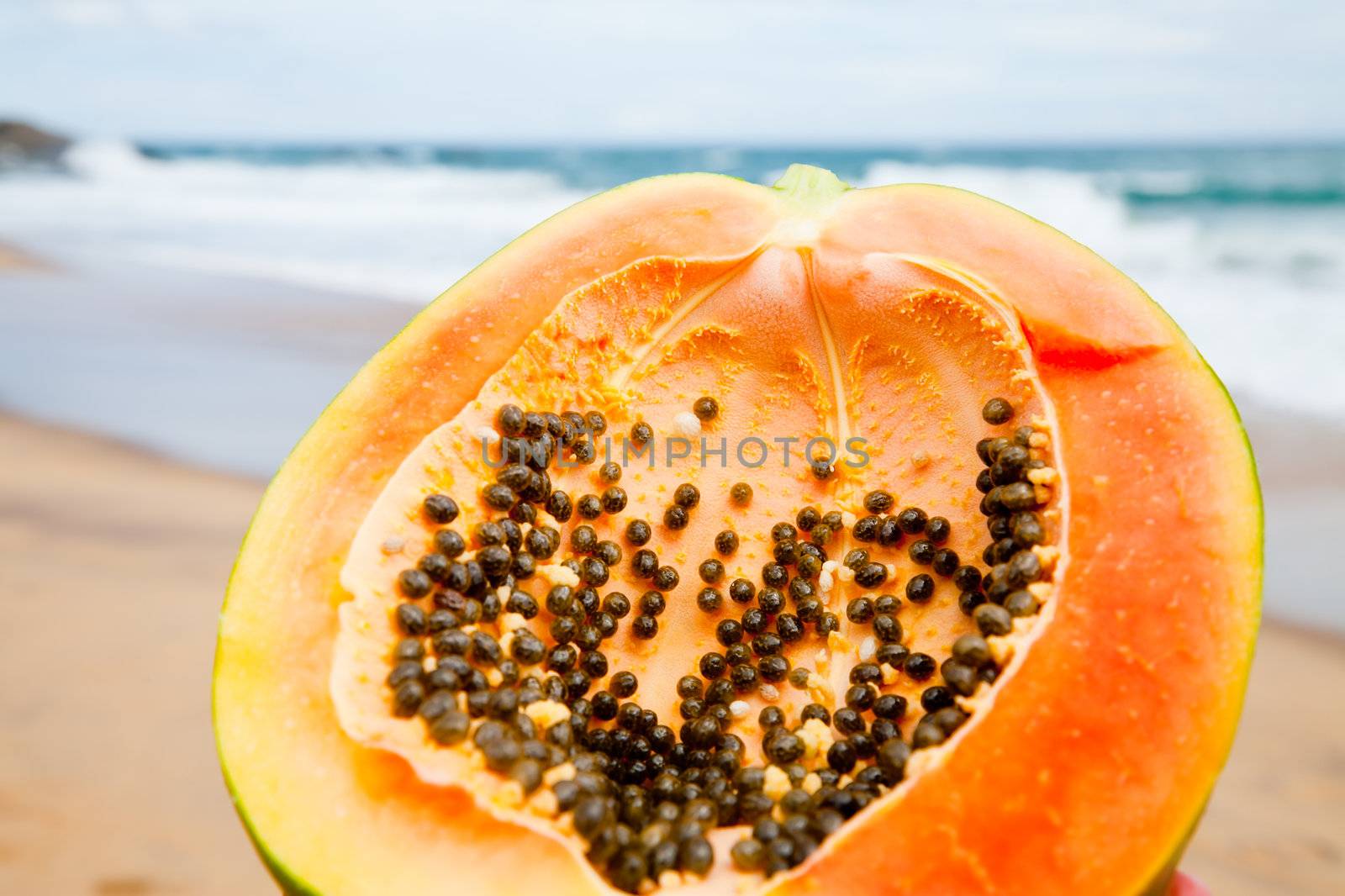 Ripe papaya cut in half on a beach