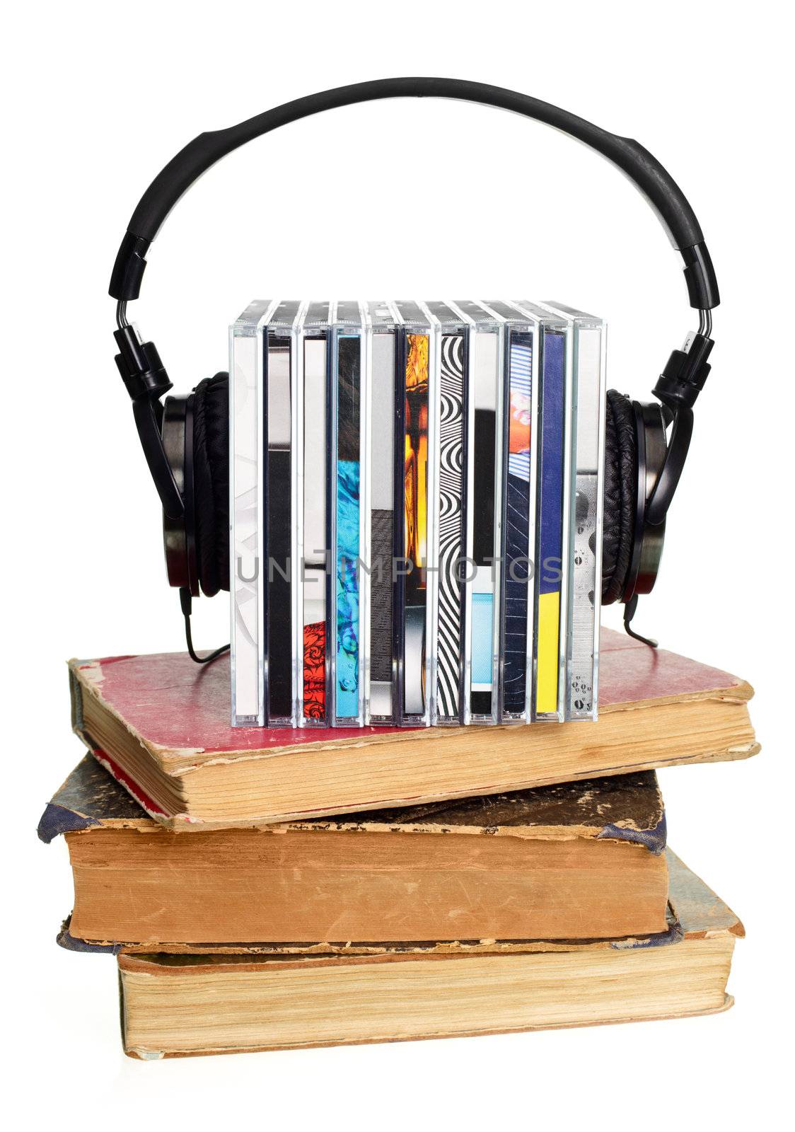 Stack of CDs with HI-Fi headphones and old books on white background