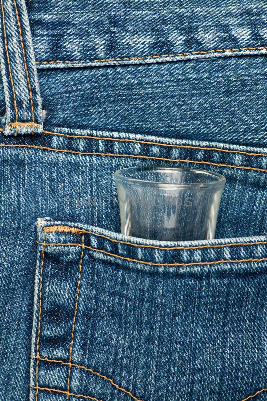 Blue jeans pocket with a shot glass