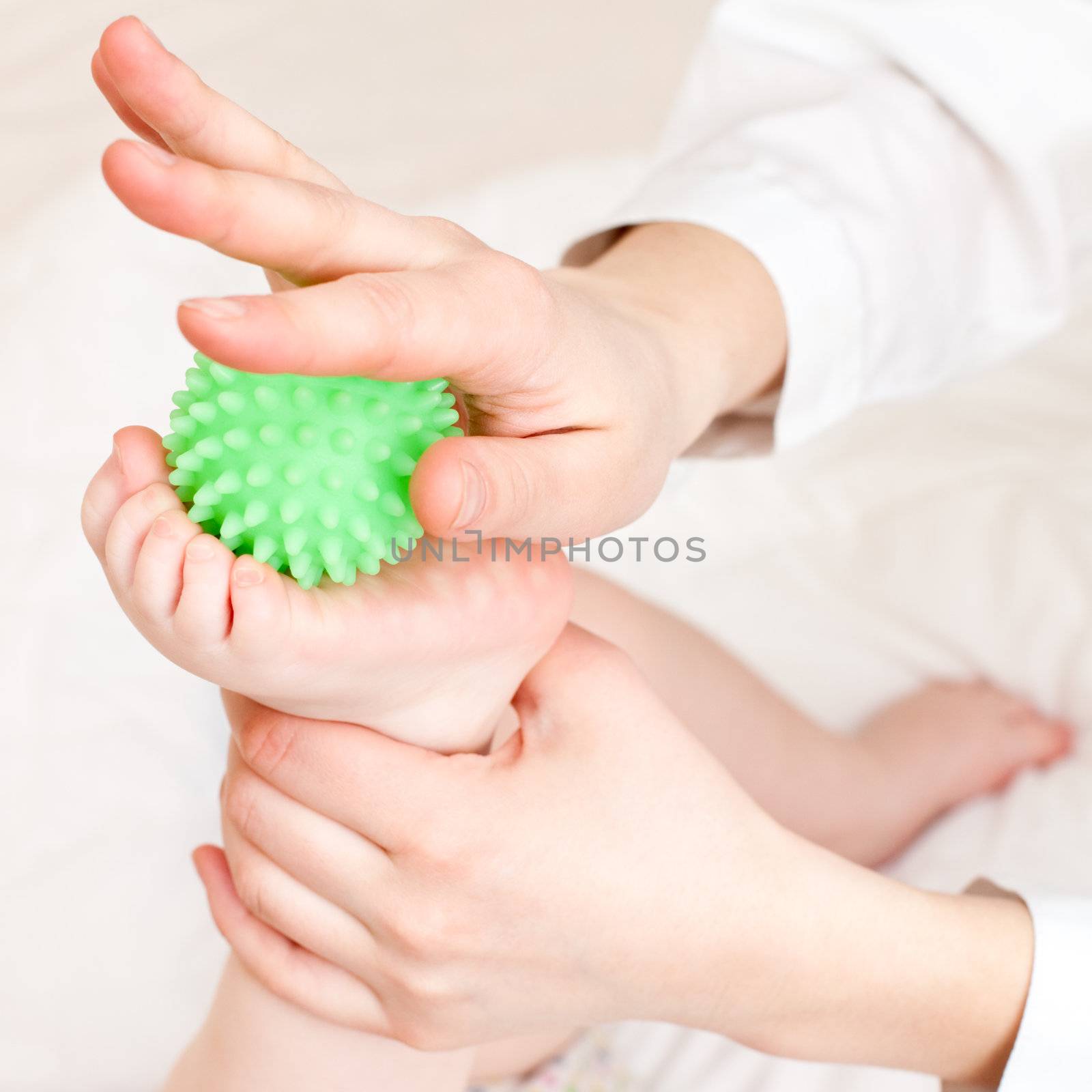 Masseur massaging child's foot with rubber device, shallow focus