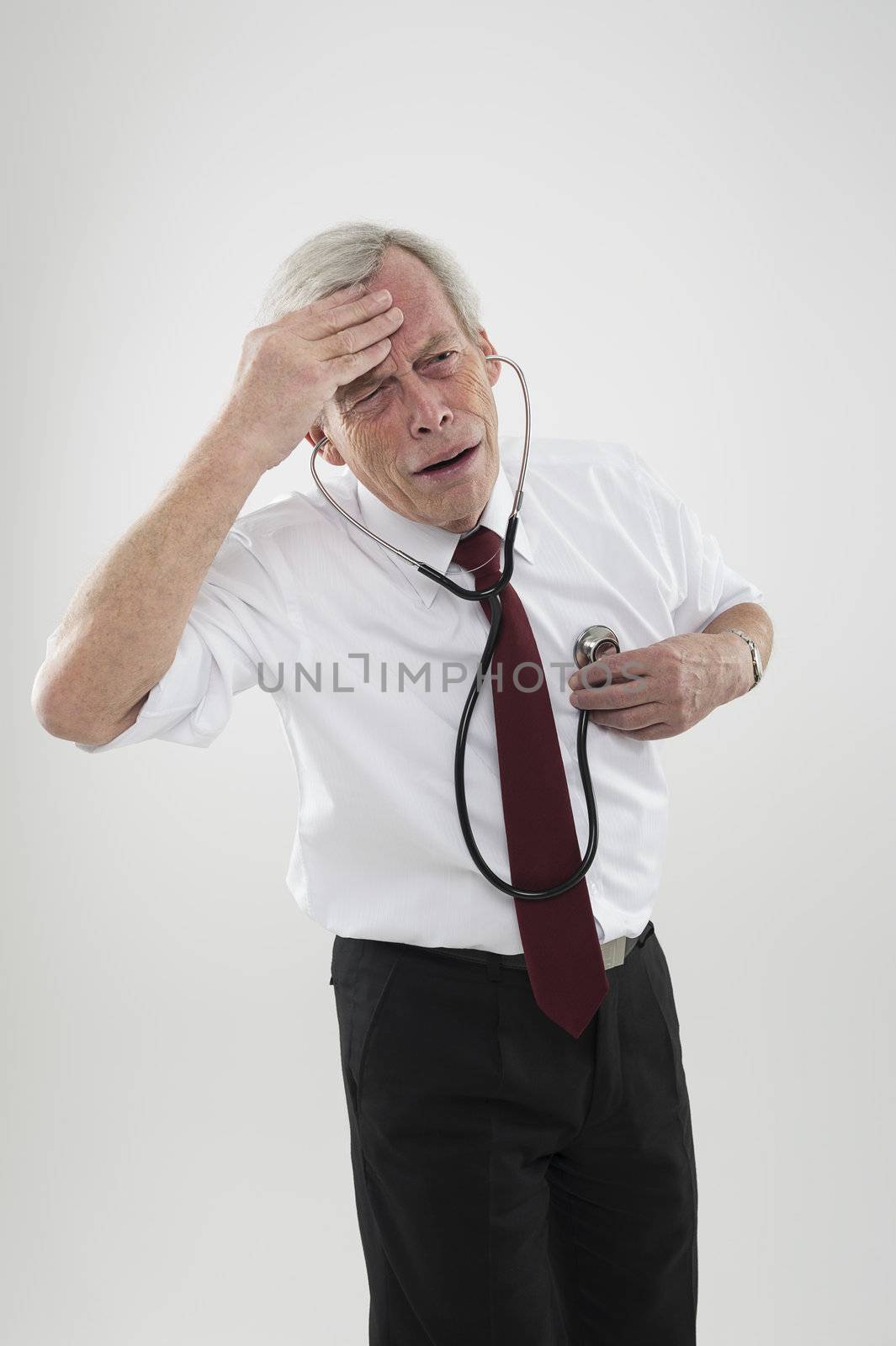 Old man, who is feeling unwell, is trying to diagnose his condition his own illness with the help of a stethoscope