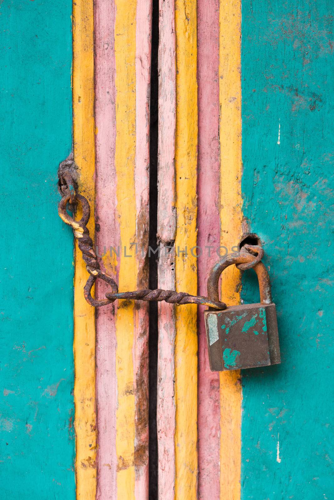 Vintage lock and chain on an old colorful wooden door 