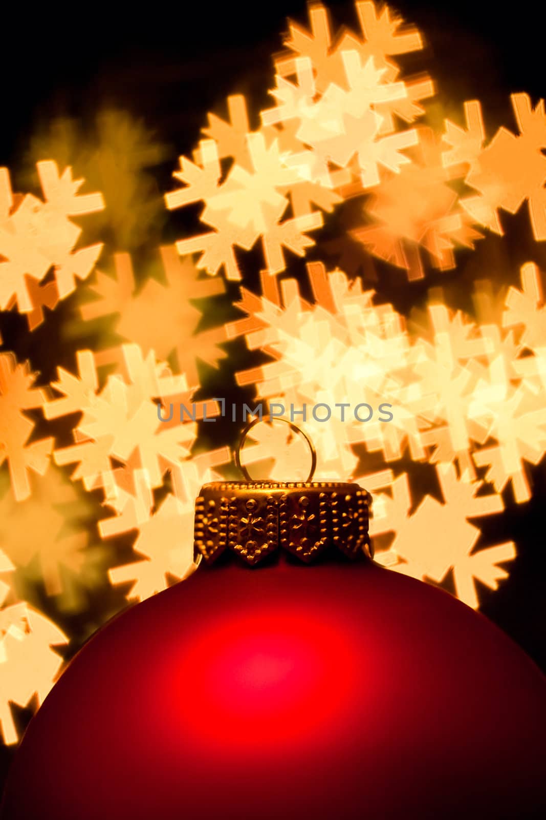 Red Christmas bauble with blured lights in a shape of snowflakes in background, very shallow DOF