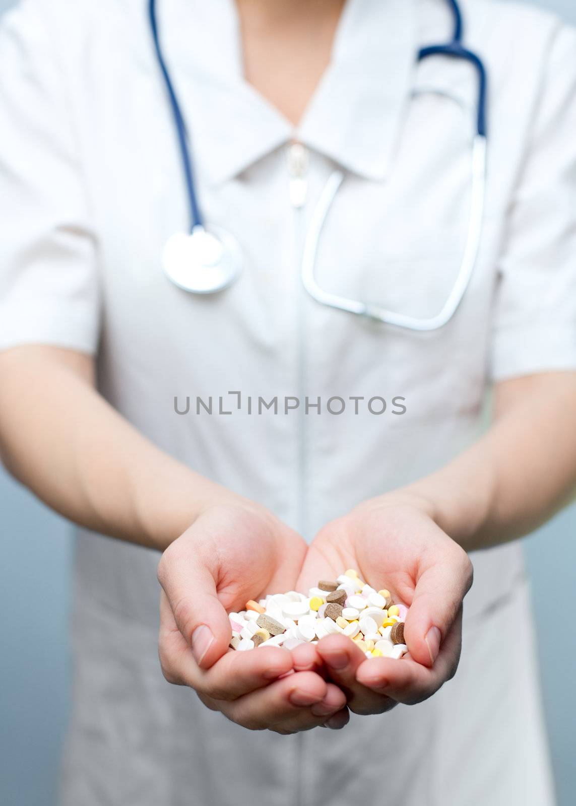 Closeup of doctor holding heap of tablets in her hands, focus on tablets