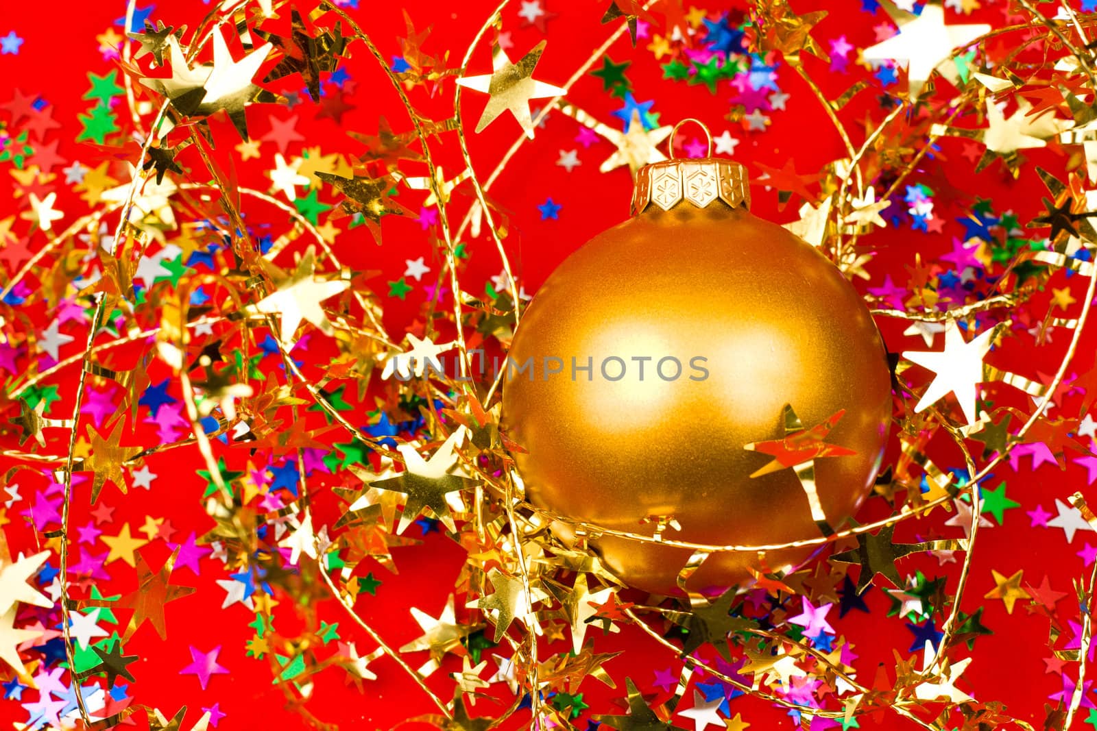 Golden Christmas bauble with star shaped tinsel on red background