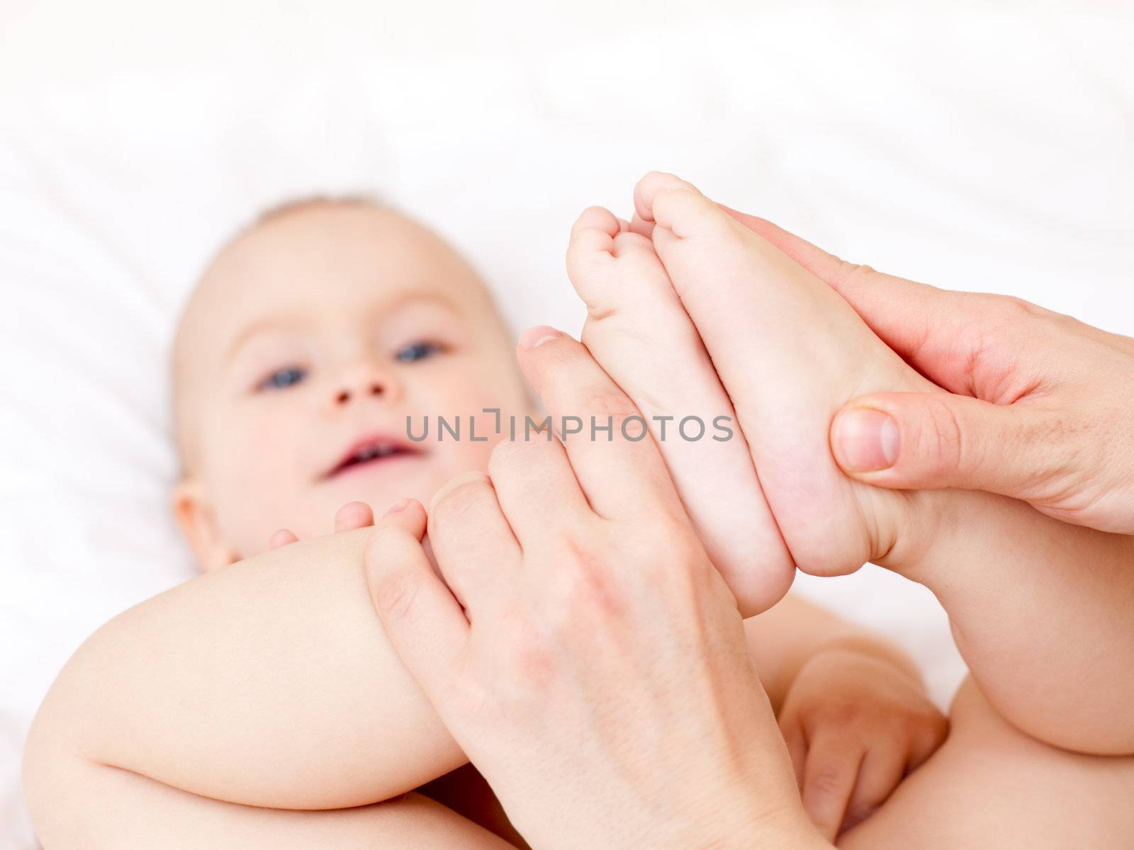 Masseur massaging little baby's feet, shallow focus