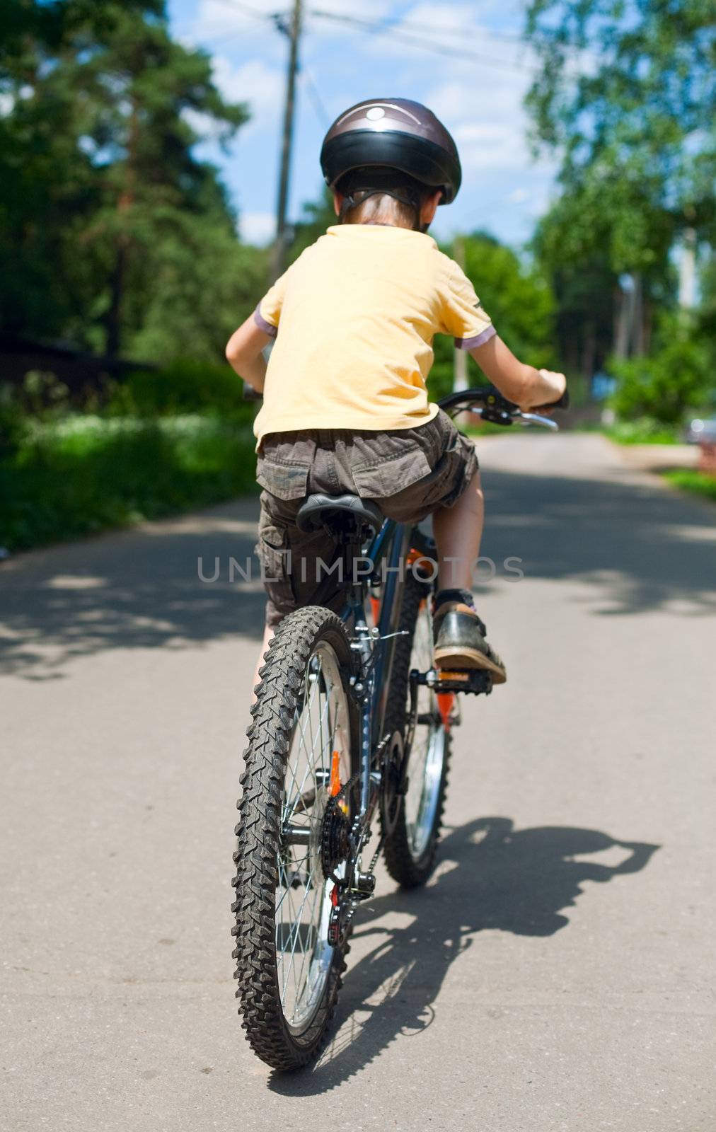 Young boy riding bicycle, shallow dof, focus on rear wheel