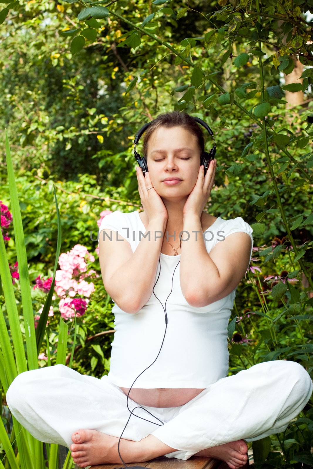 Young woman listening to a music in a summer garden