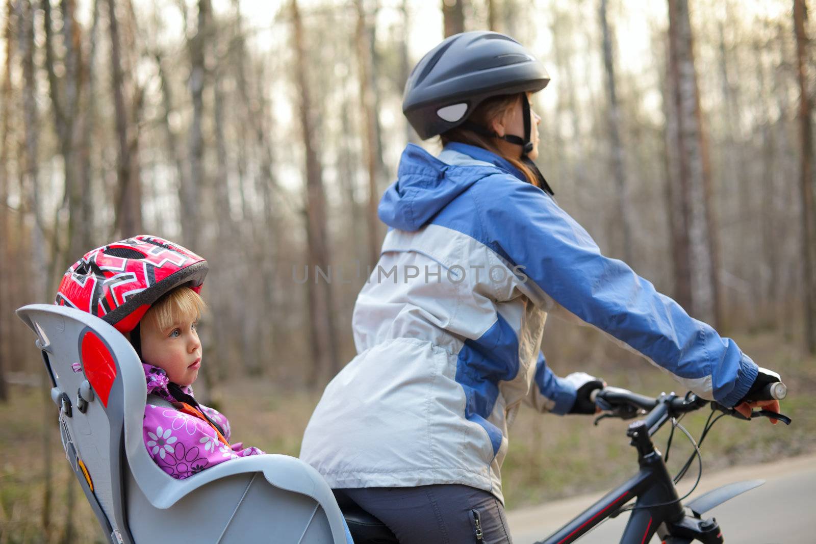 Mother riding on a bicycle with little girl, focus on child