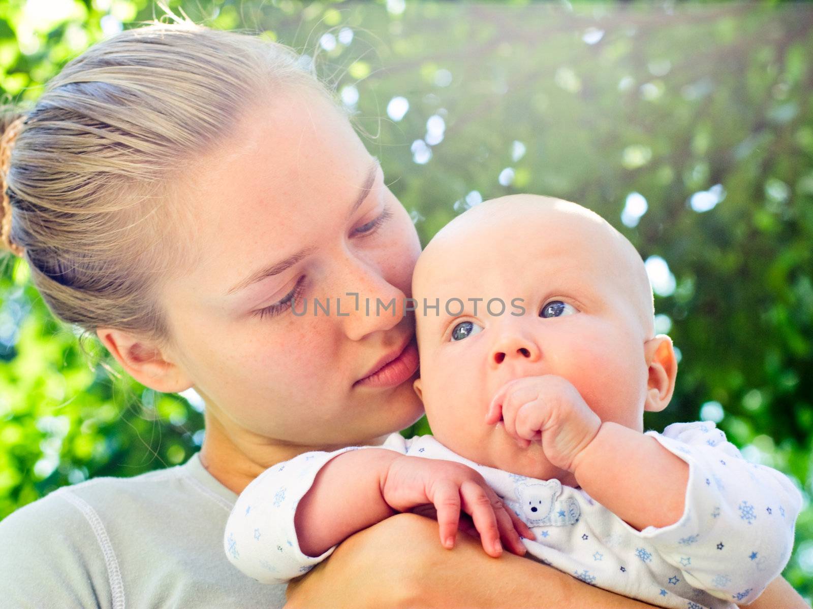 Young woman holding baby girl in a summer garden