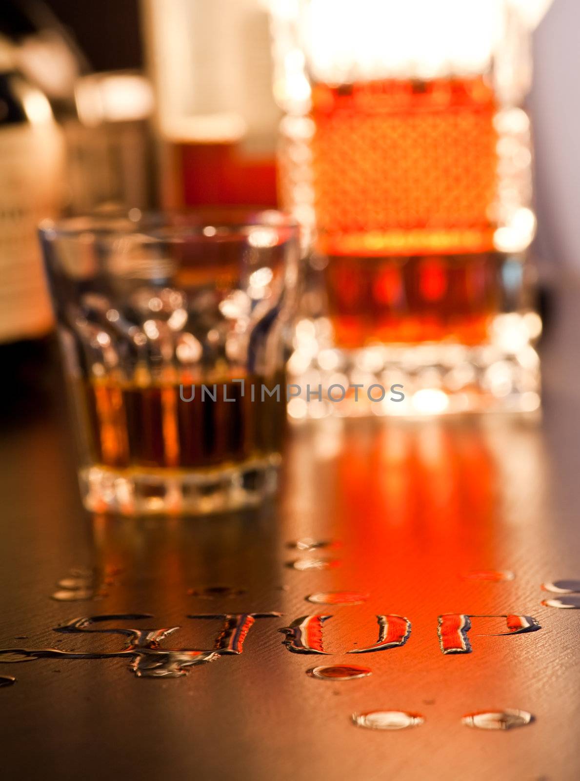The word Stop written with spoiled whiskey on a table, shallow DOF