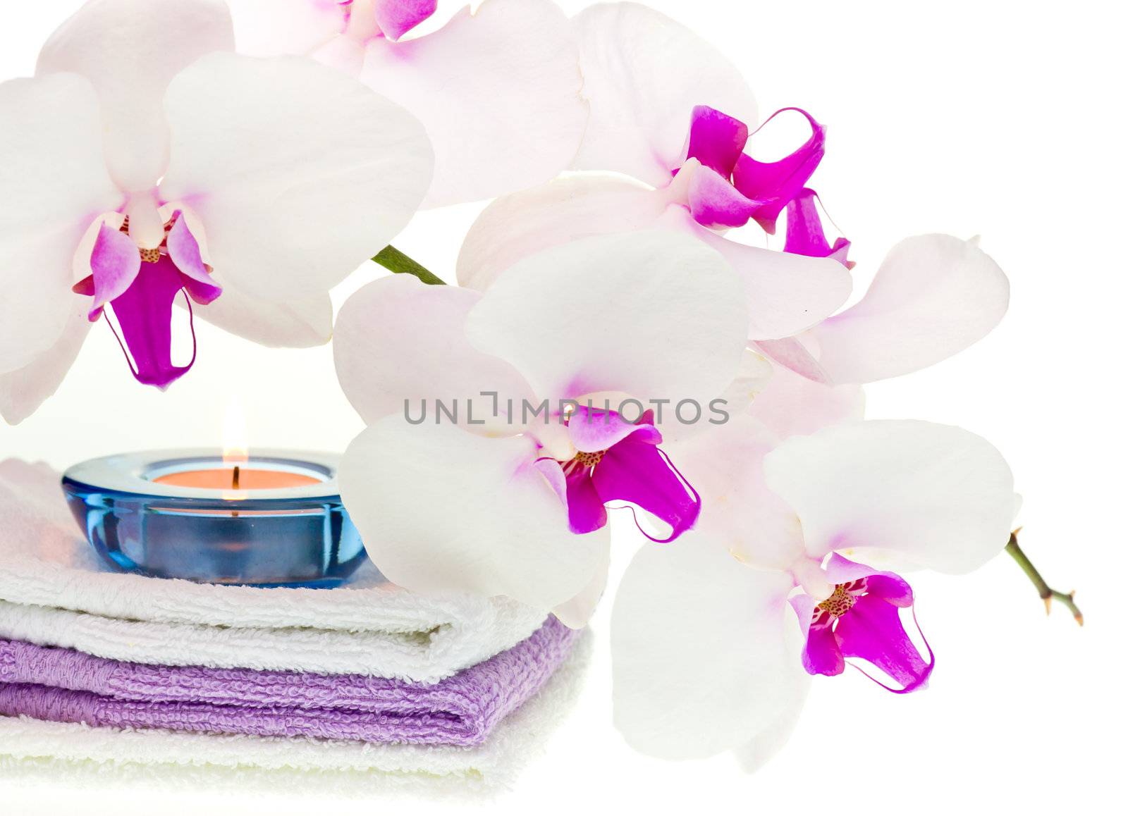 White orchid, towels and burning candle on white background