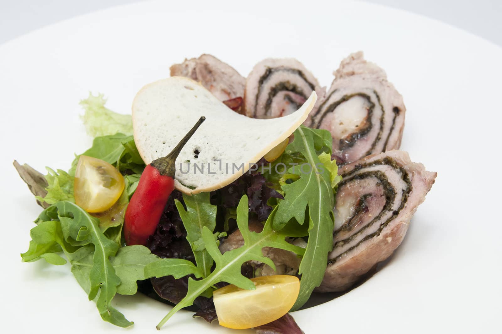 Roll meat with herbs and vegetables on a white plate