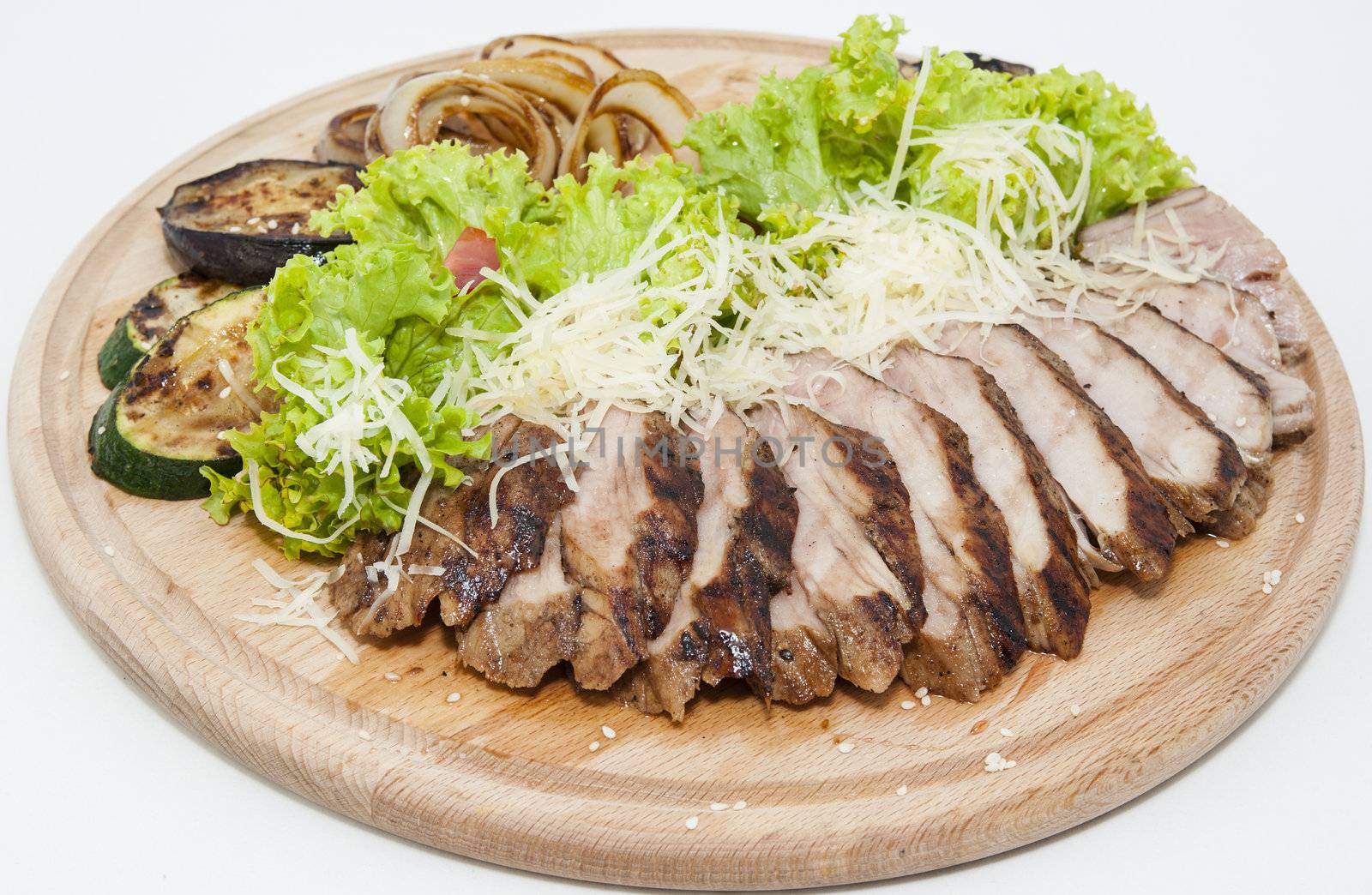 meat roasted on a grill with vegetables on a wooden plate