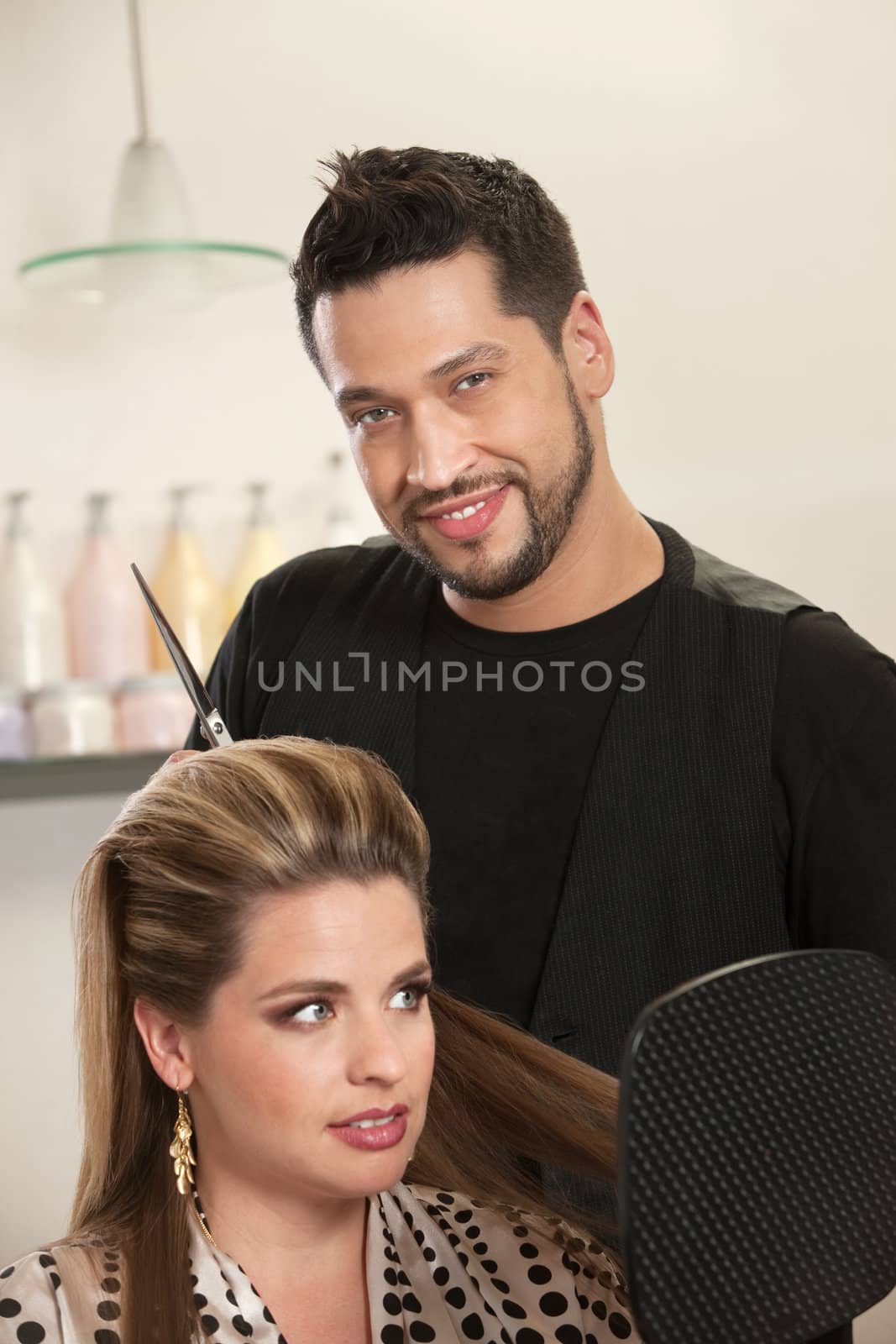 Attractive male Hispanic hairdresser with smiling customer