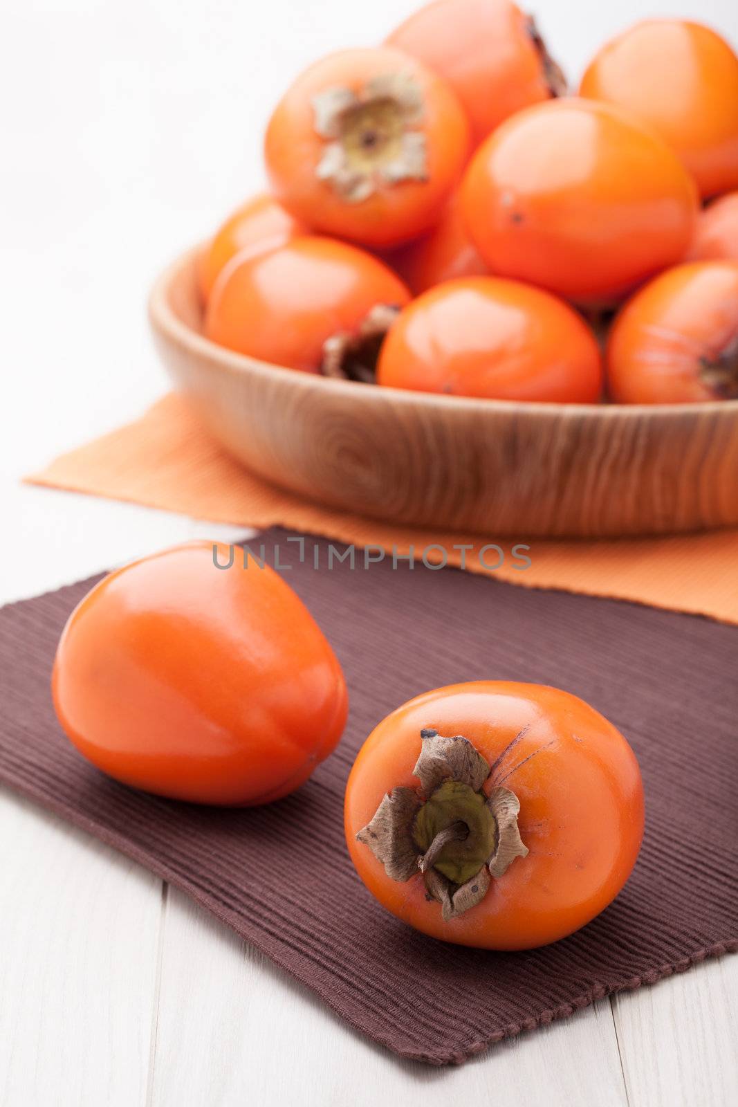 Fresh exotic tropic ripe juicy orange fruits  persimmon Diospyros served in wooden plate on table