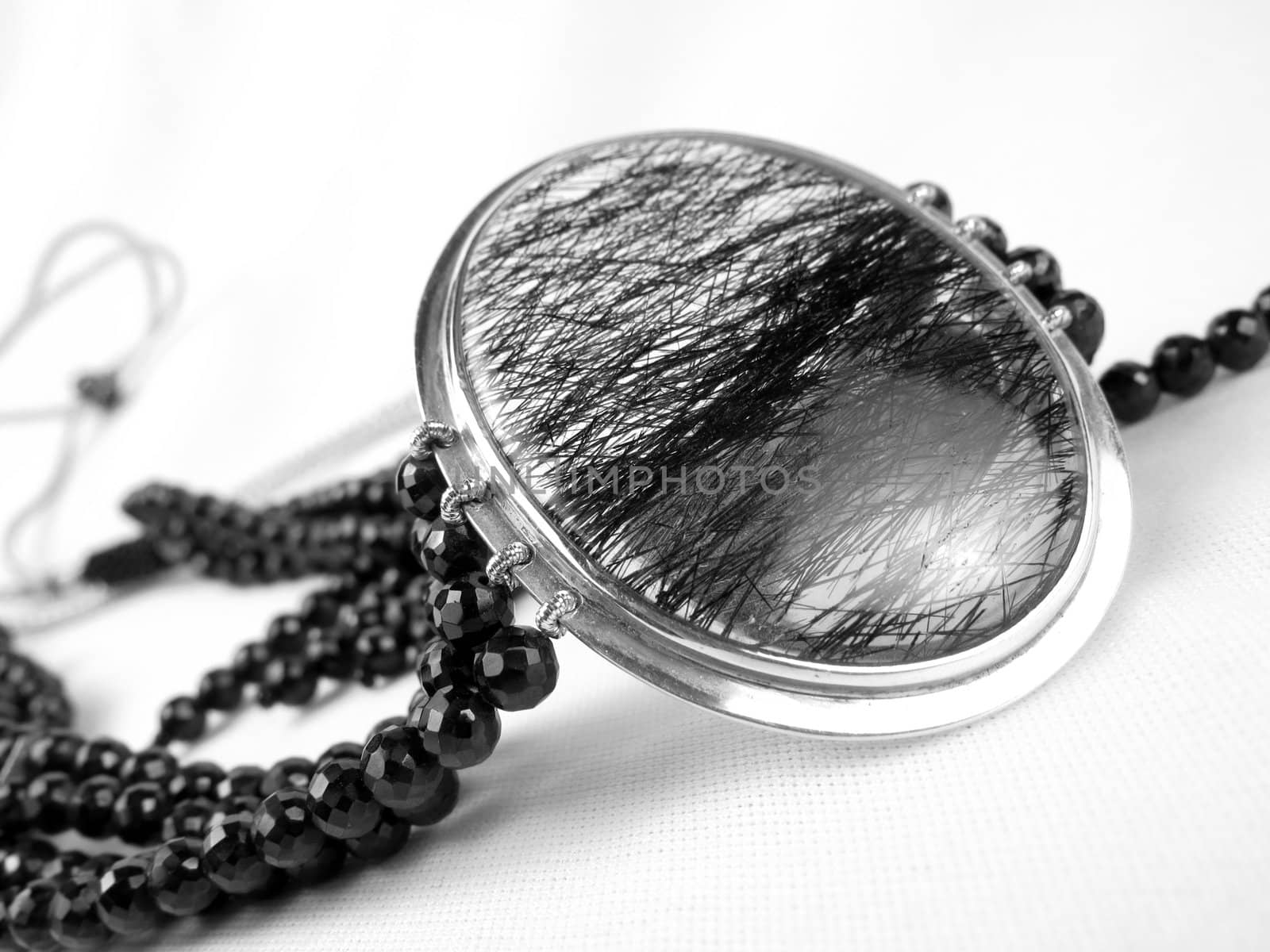 A beautiful designer necklace made of a silver pendant and black crystals.                               