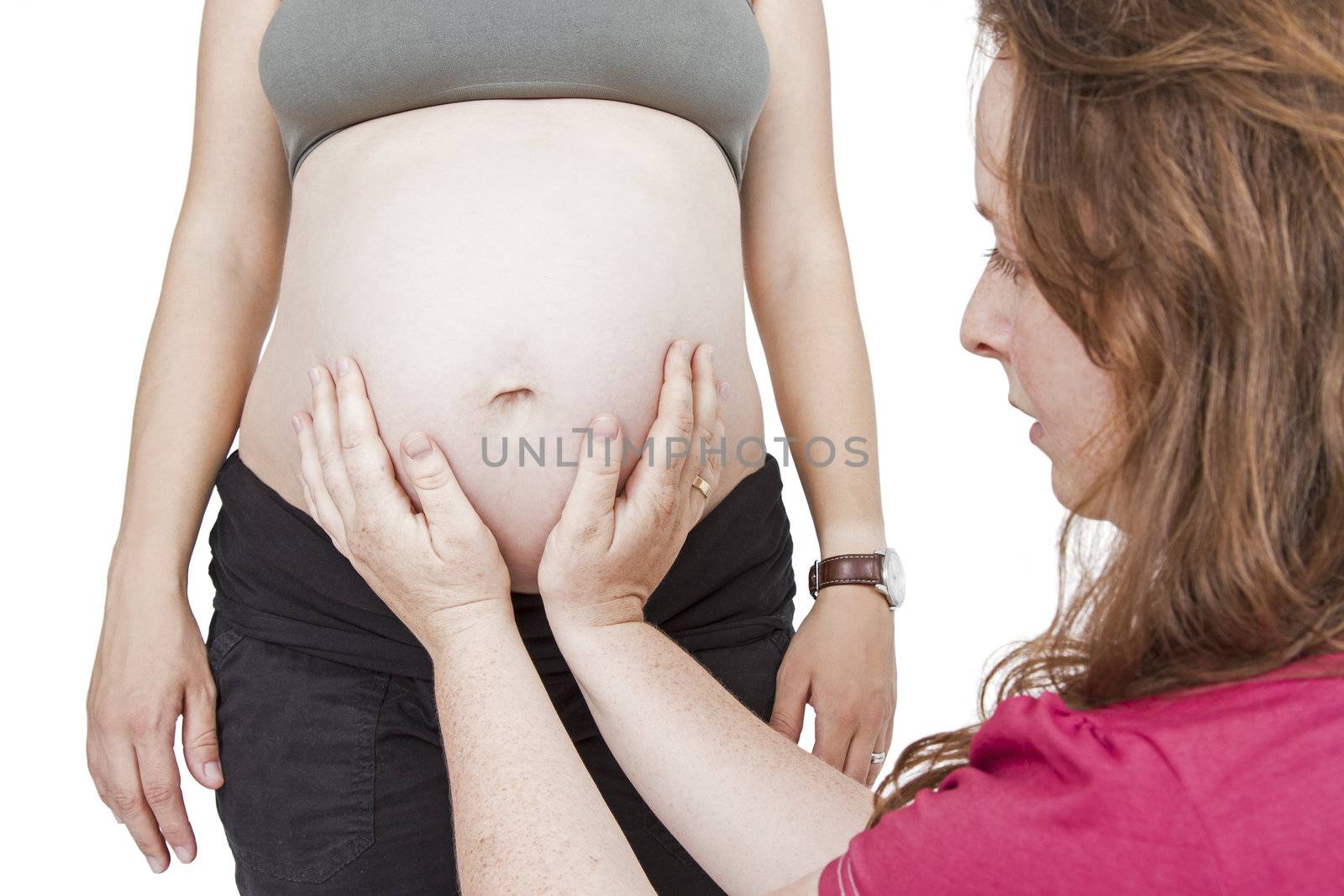 young midwife fingering at human belly. pregnant woman standing while midwife is sitting in front. horizontal picture isolated on white
