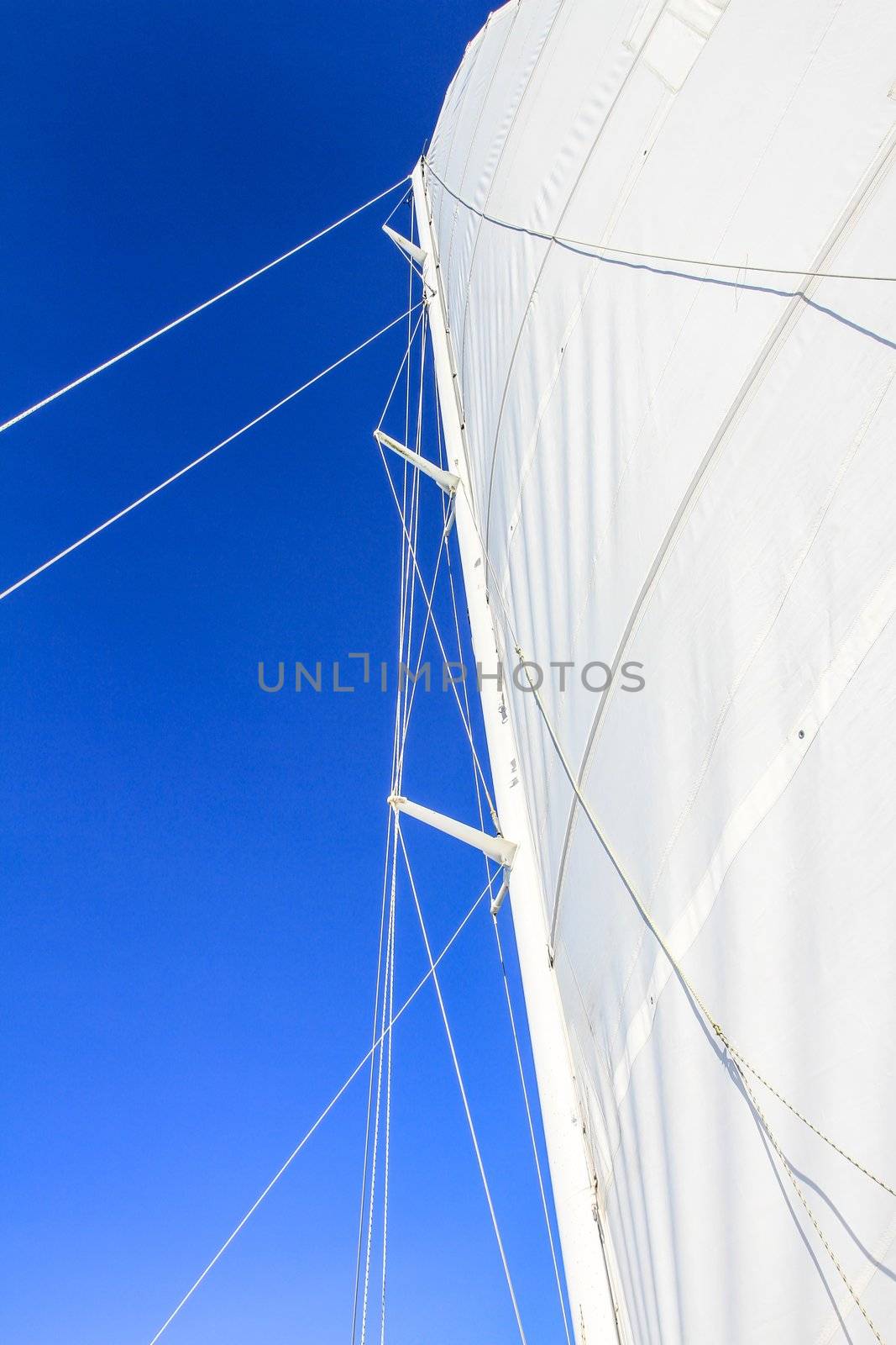 View at the bottom looking up at boat mast with rigging and blue sky