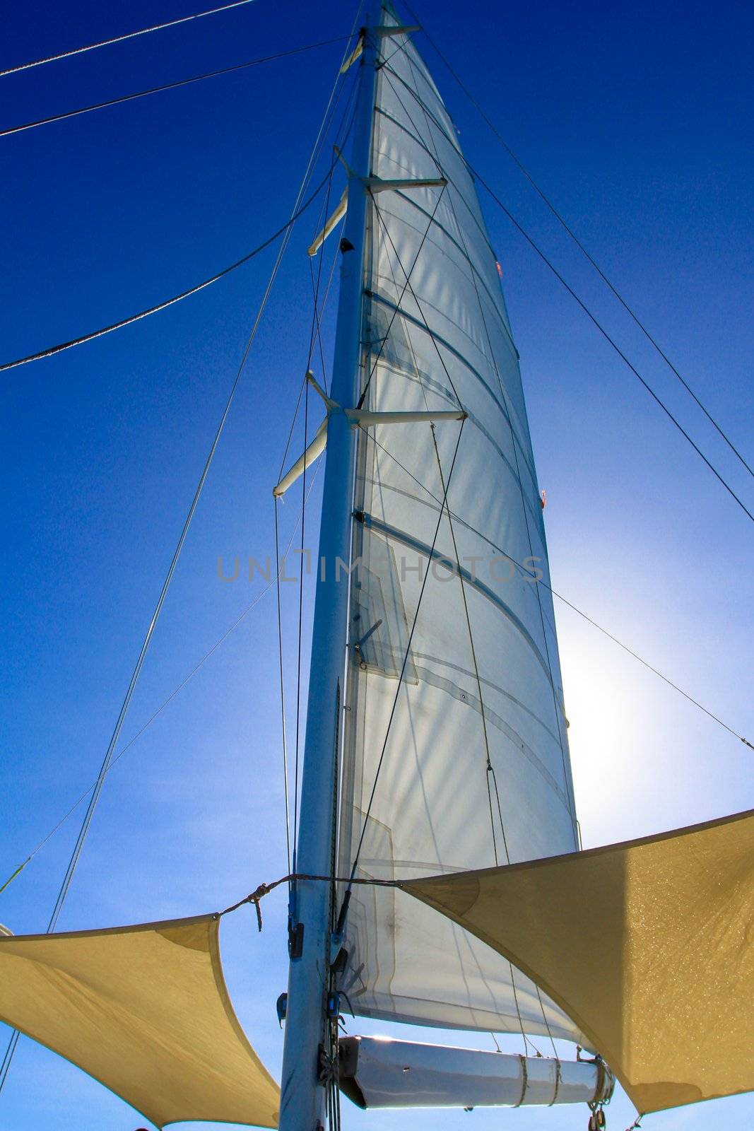 View at the bottom looking up at boat mast with rigging and blue sky