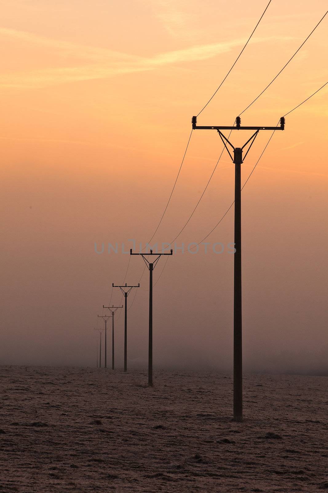 Power-transmission poles in the mist in winter nature