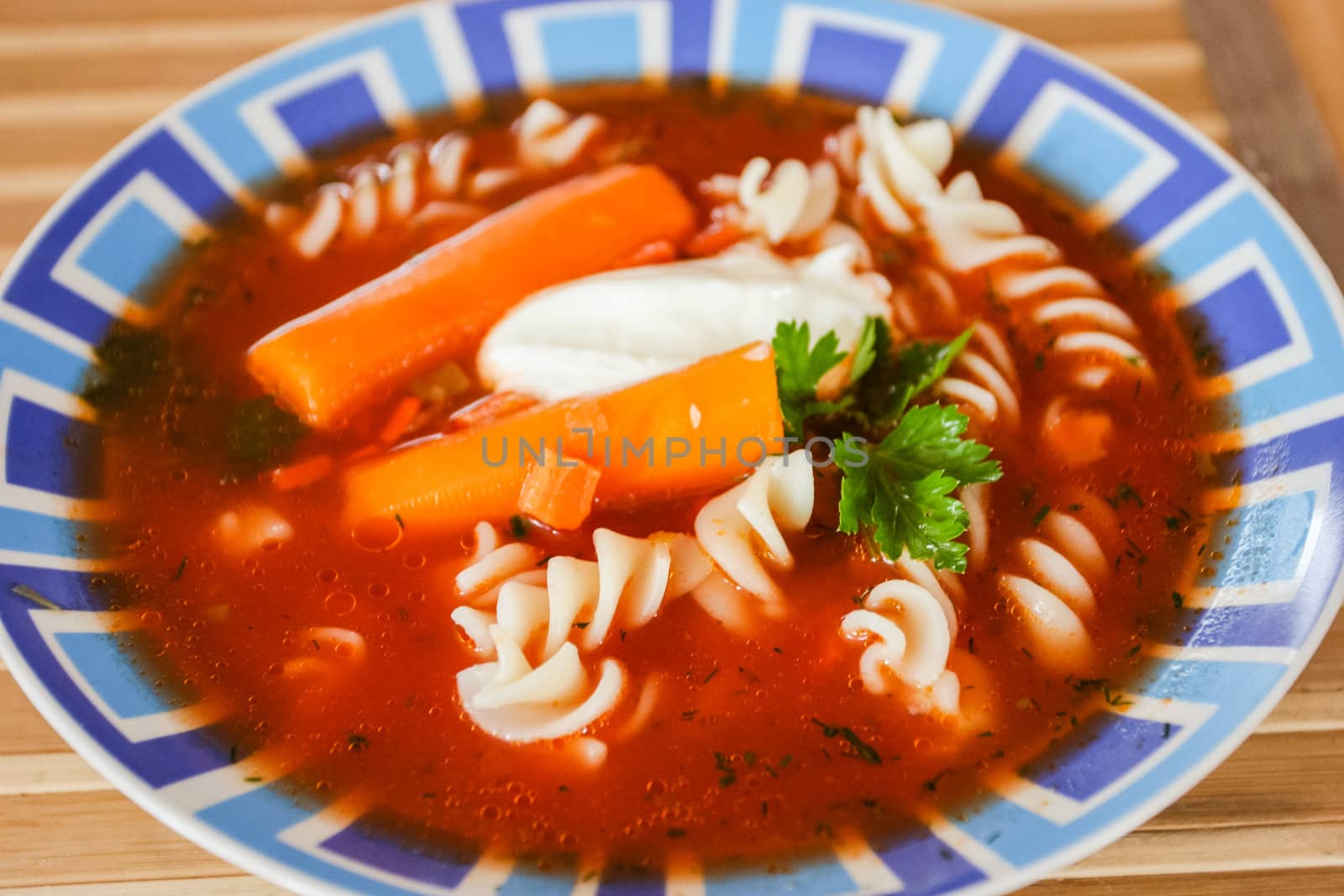 Traditional polish tomato soup with noodles and carrots.
