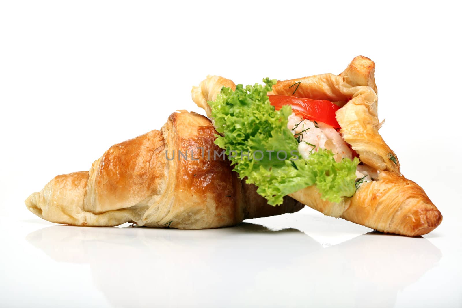 Close up of two tasty croissants with salad and tomato inside