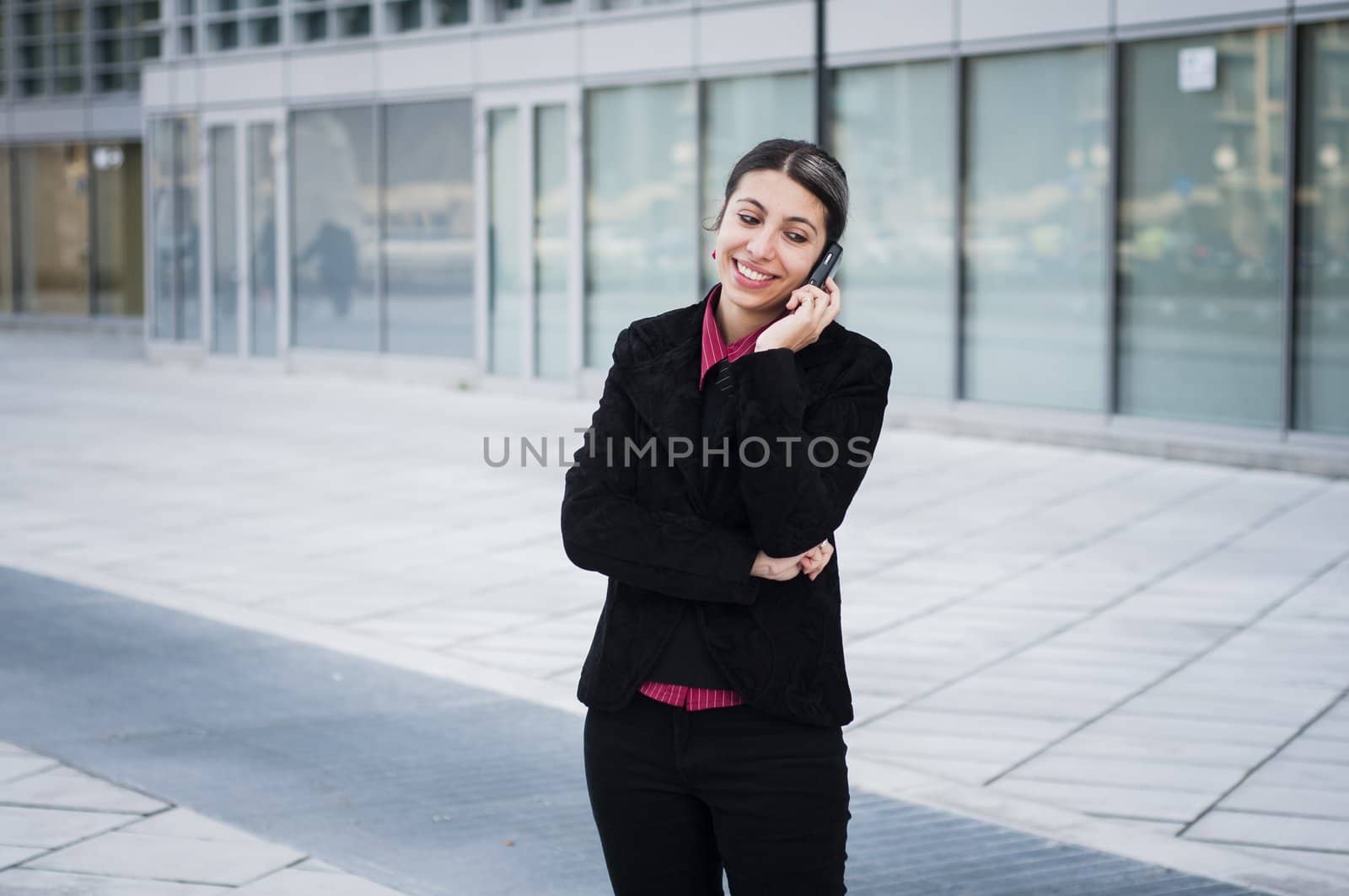 smiling business girl on the phone in front of a modern building