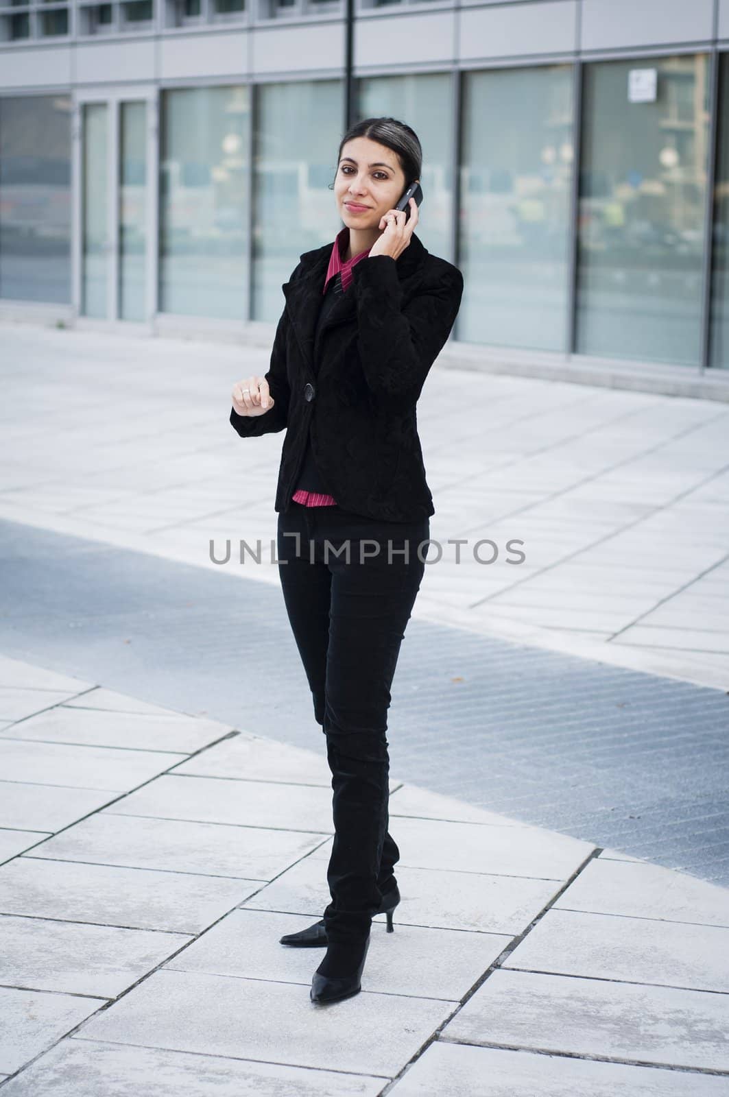 smiling business girl on the phone in front of a modern building