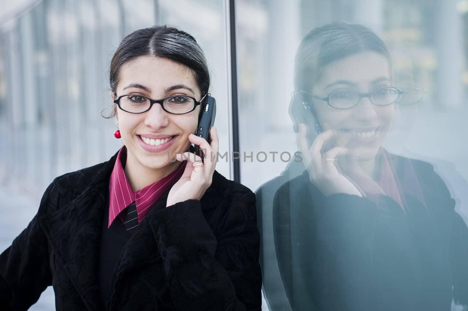 smiling business girl on the phone in front of modern building
