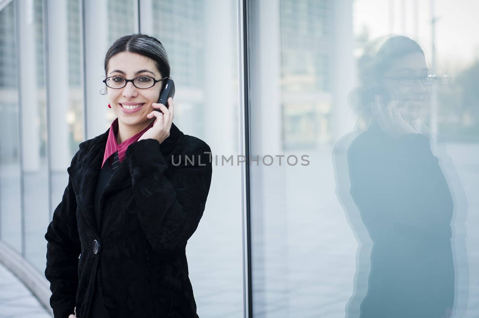 smiling business girl on the phone in front of modern building