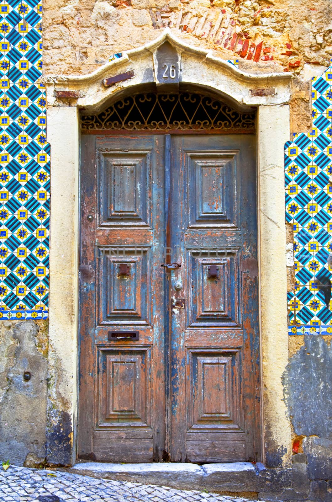 Old wooden door in Portugal. Wall of traditional Portuguese tiles
