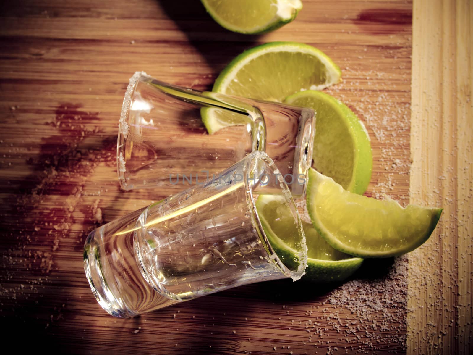 Two empty shot glasses left from tequila, wedges of lime, and salt