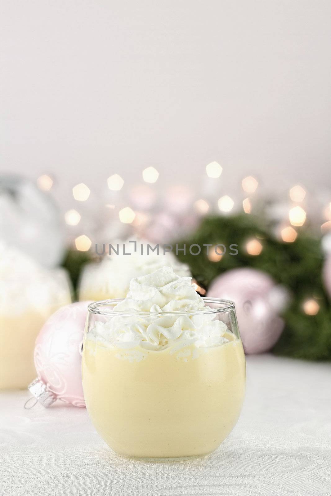 Eggnog with Christmas decor in the background. Shallow depth of field with selective focus on glass in foreground.