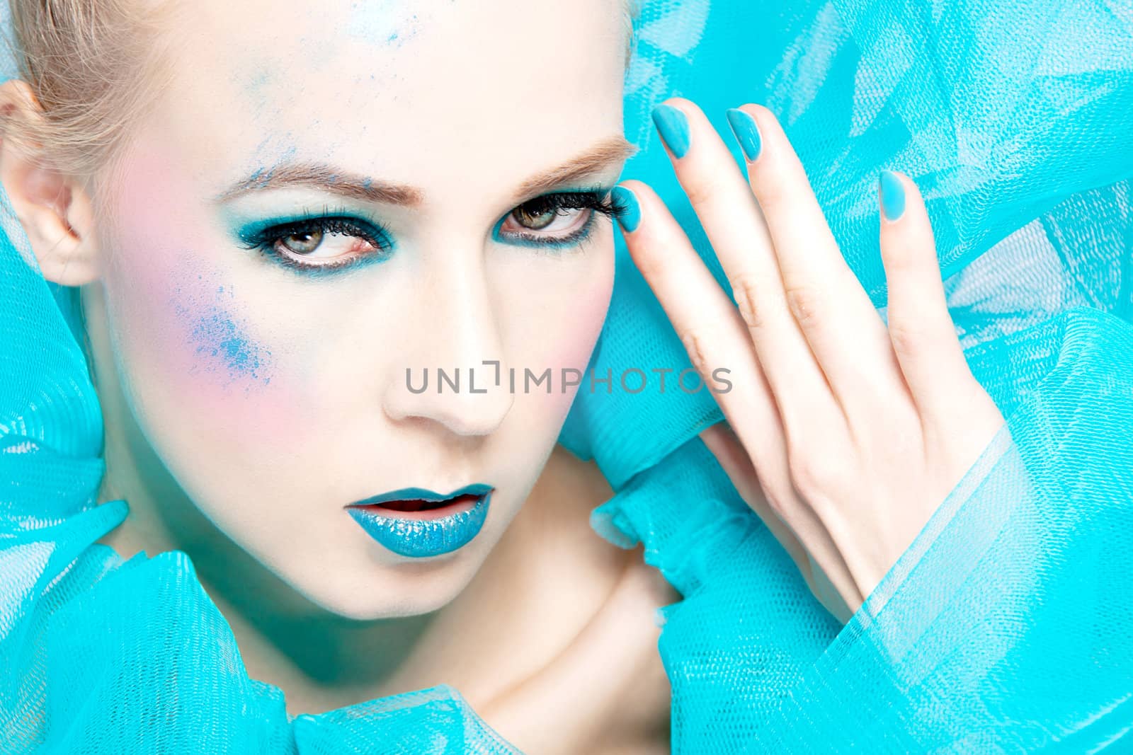 beautiful woman with extreme colorful make up in turquoise closeup