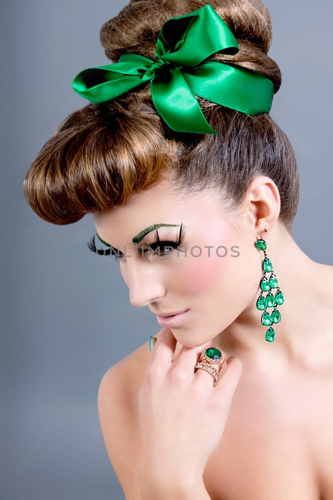 brunette woman with green jewelery and accssesoires on grey background