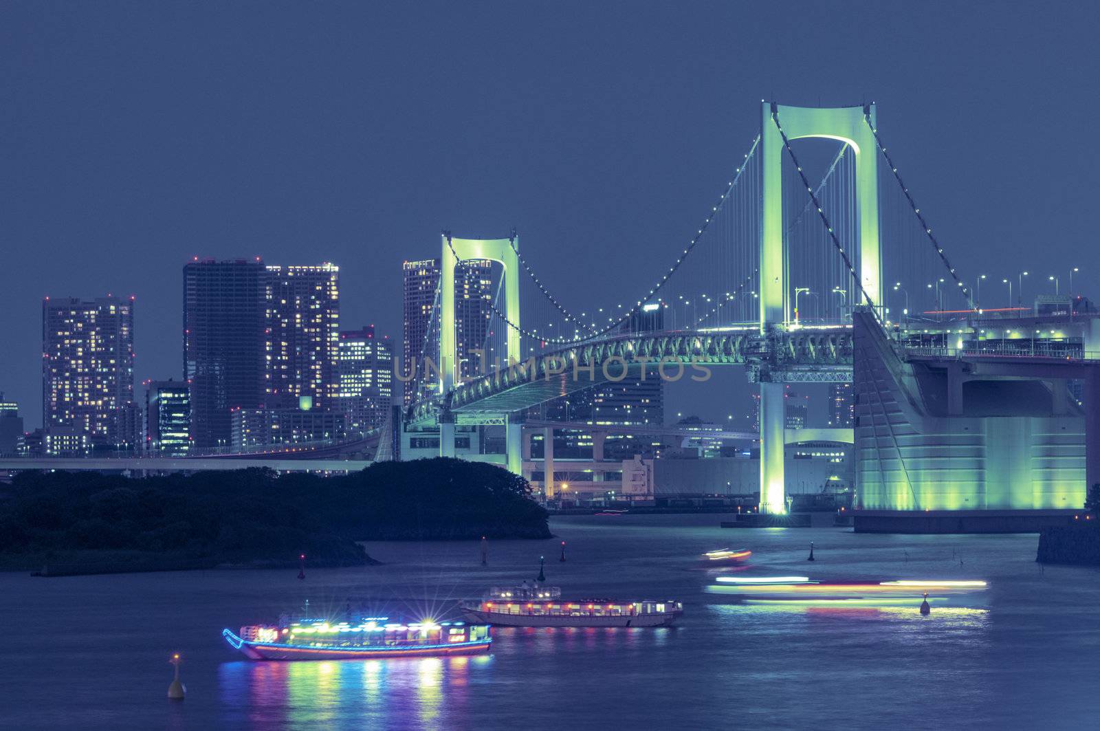 famous landmark, Tokyo Rainbow Bridge over bay waters with scenic night illumination and traditional Japanese boats