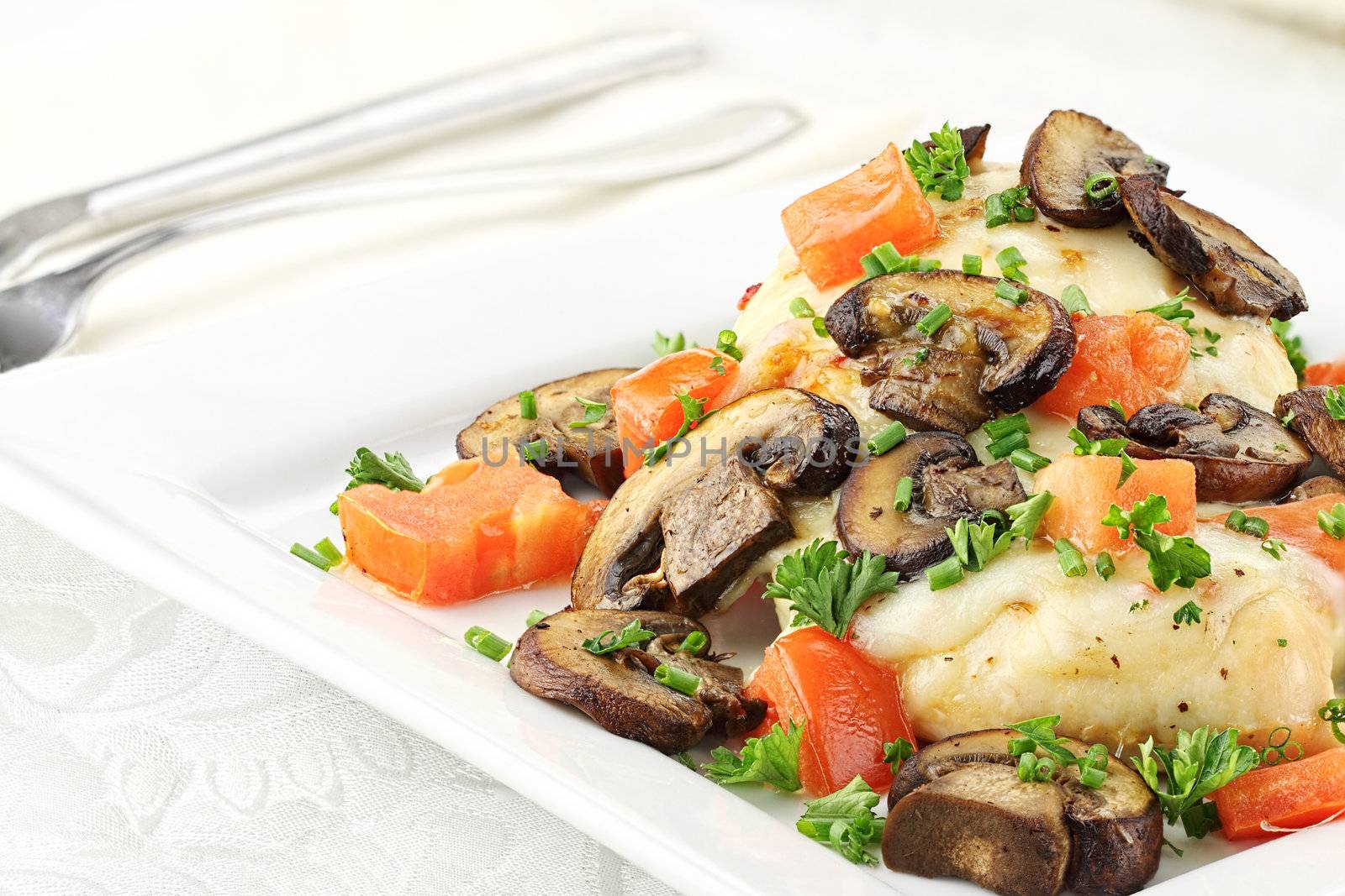 Chicken baked with baby portabella mushrooms, tomatoes, and mozzarella cheese. Garnished with chives and parsley.