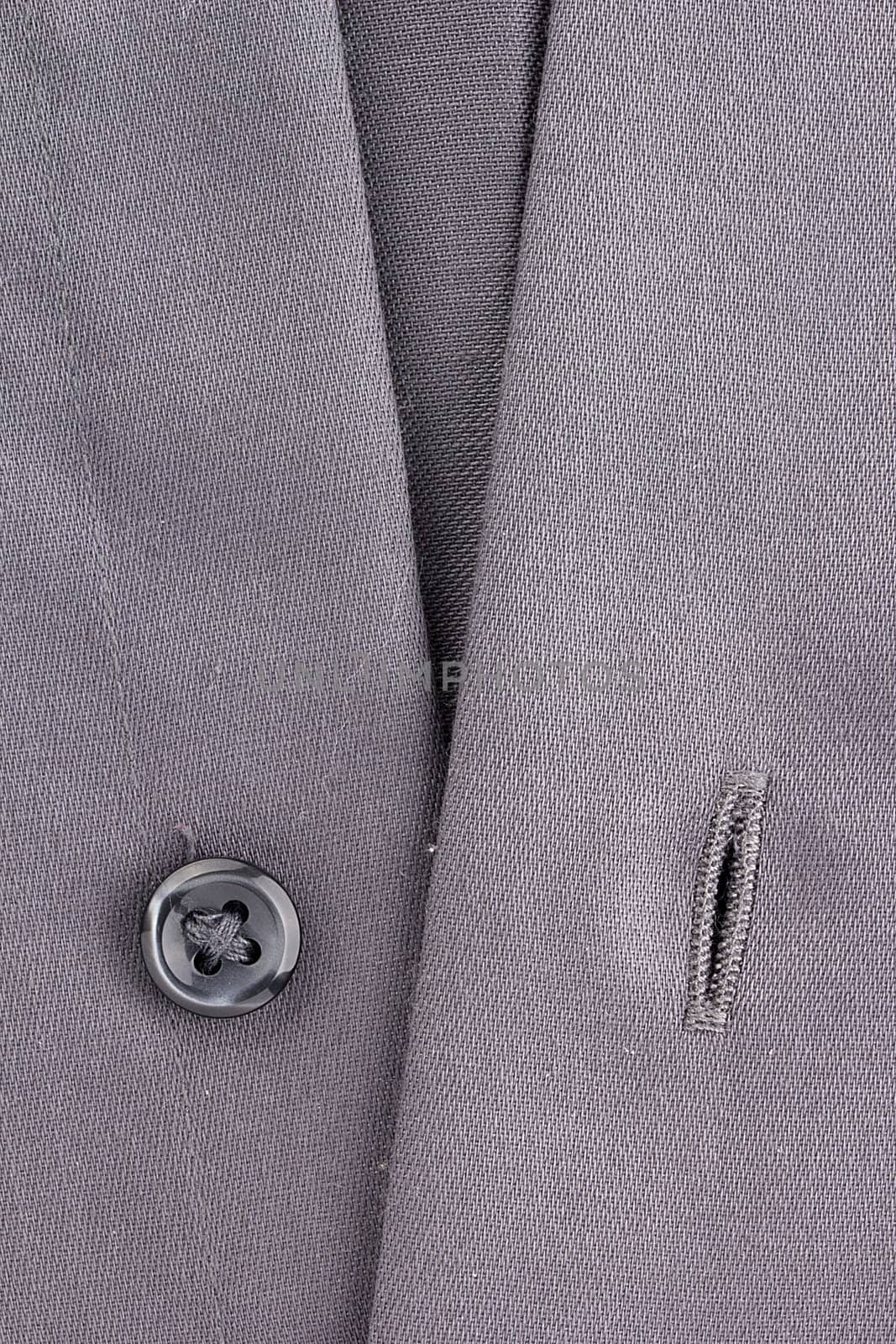 Close-up photograph of a black button on gray material.